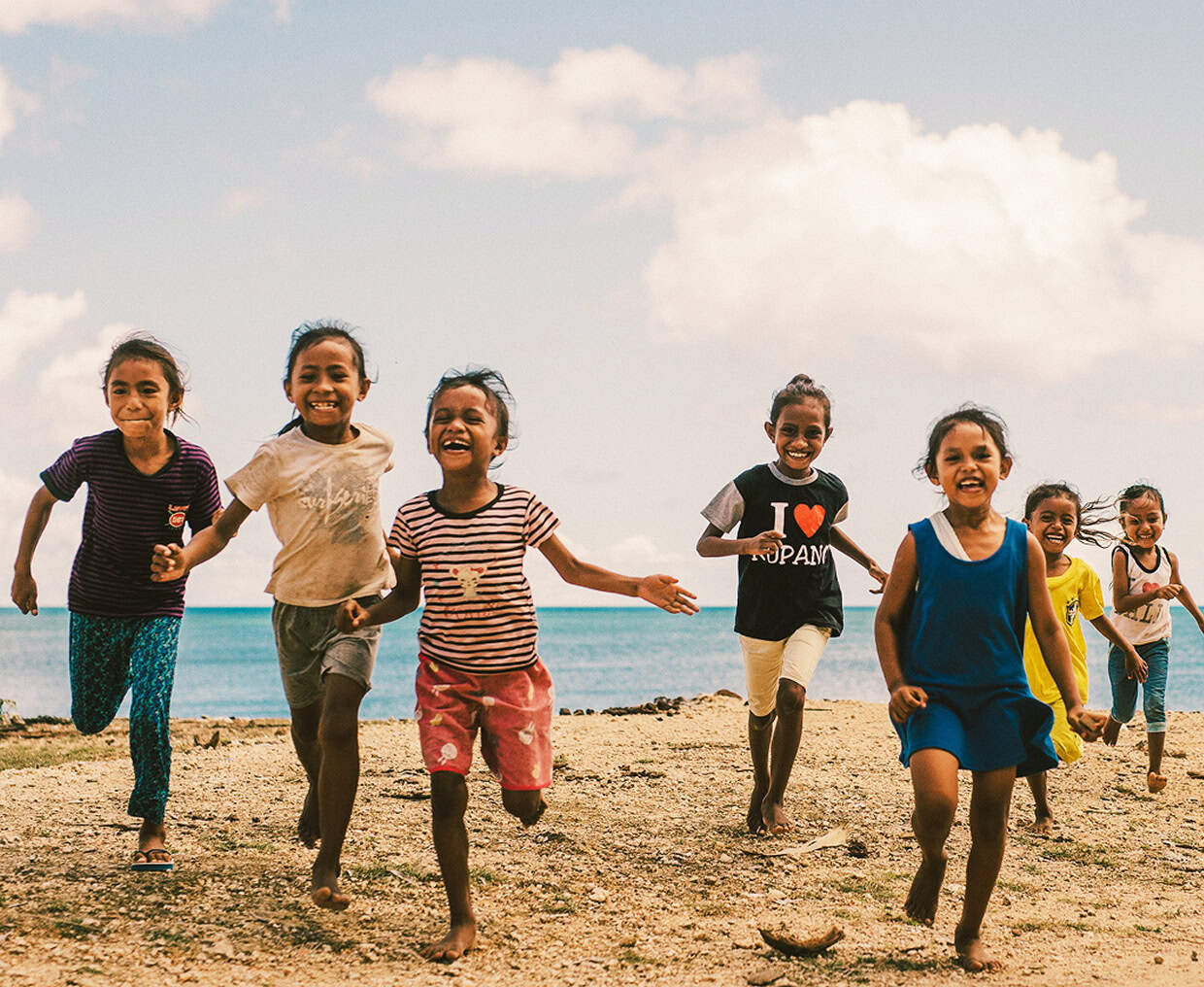 A group of children running happily on a beach.