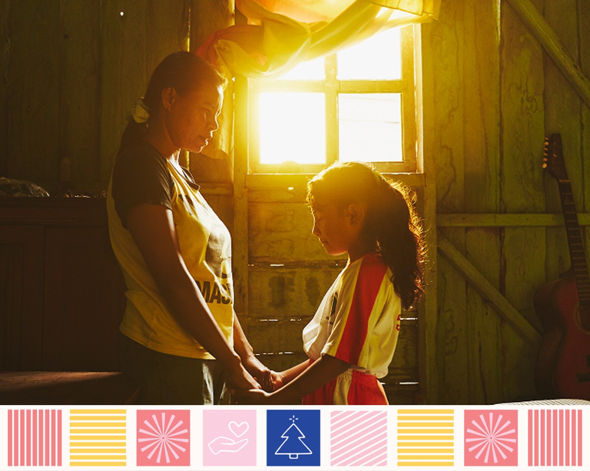 A mother holding the hands of her daughter praying.