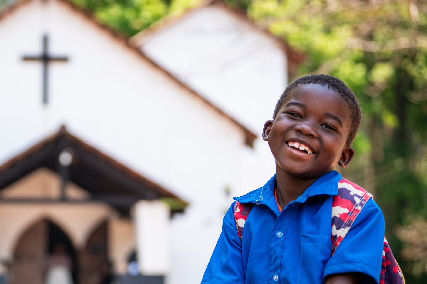 Photo of a boy smiling in front of church