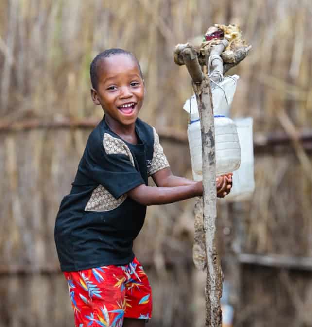 A joyful boy holding a basket of water in his hands.