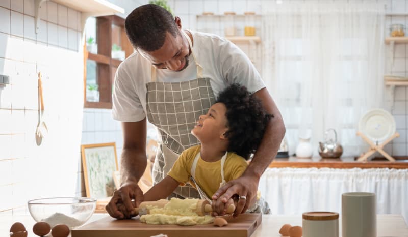 Father helping daughter baking.