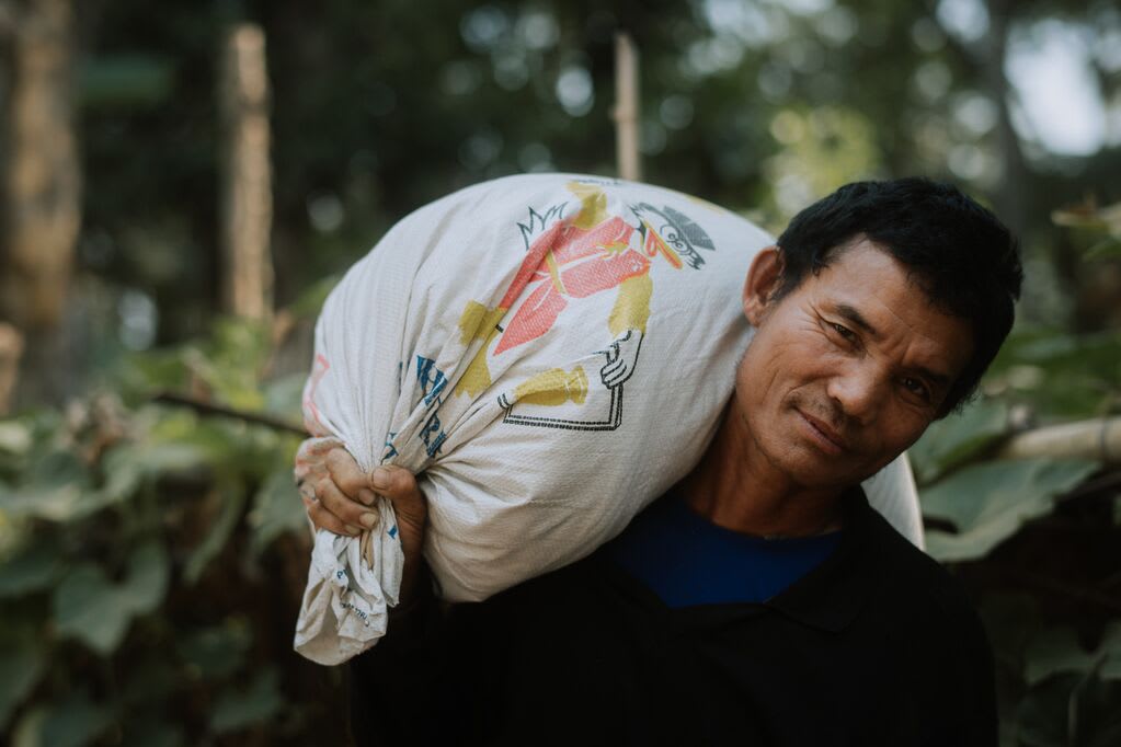 A man carries a large bag of rice.