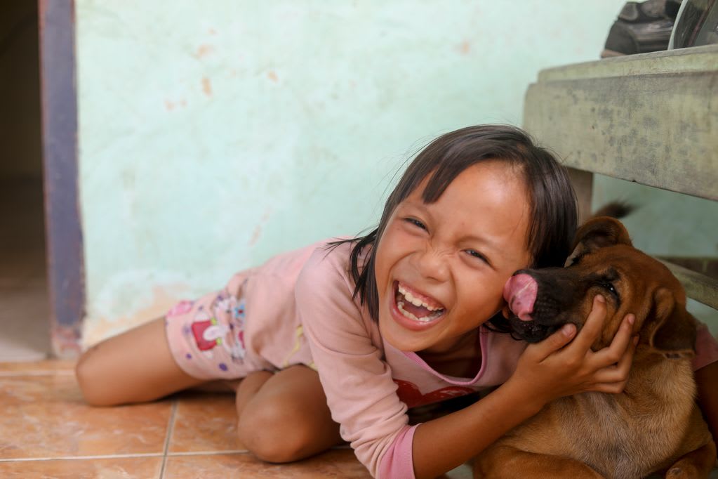 A little girl, female child, wearing a pink shirt is posing, playing with her dog named Kopi at her terrace.