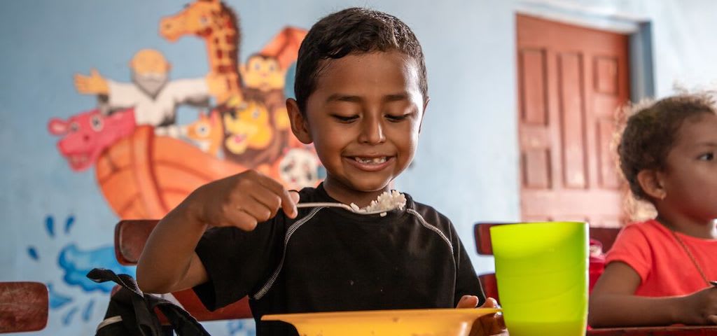 A boy eats a meal with a spoon.
