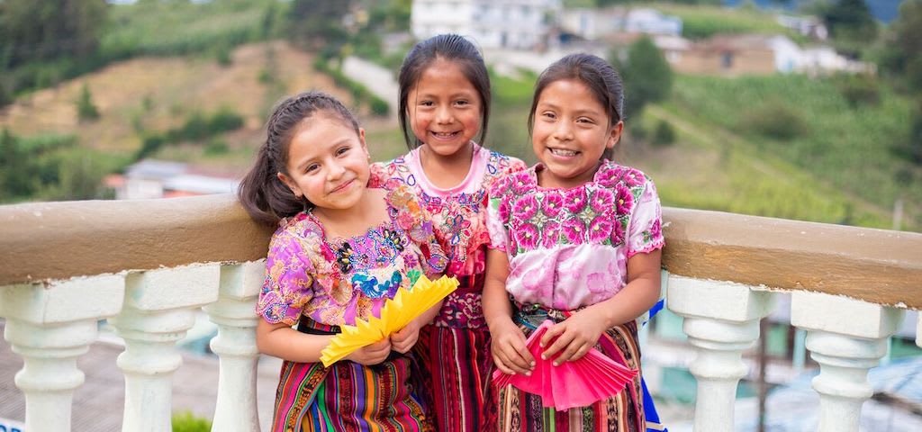 Three girls in traditional Guatemalan dresses.