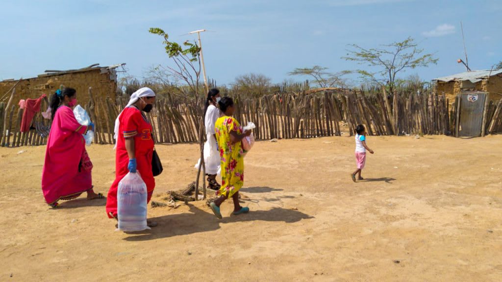 4 women are pictures arrying water and food packs through the desert.