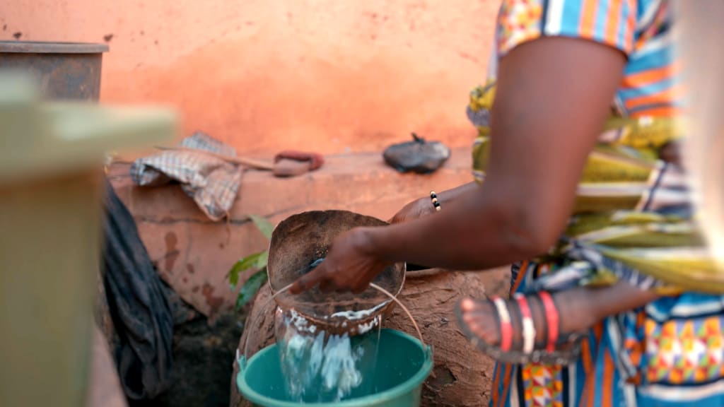 A woman pours water into a green bucket