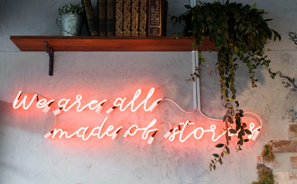 Neon sign reads "We are all made of stories"