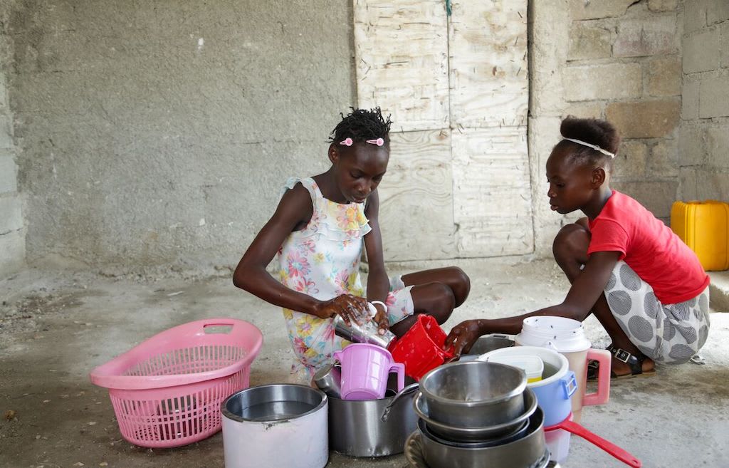 Shamaïka washes the dishes with her sister.