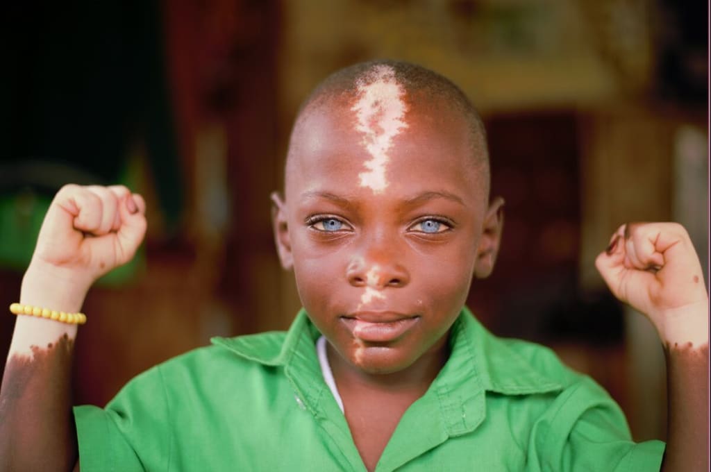 Close up of a little boy wearing a green shirt and flexing his arms