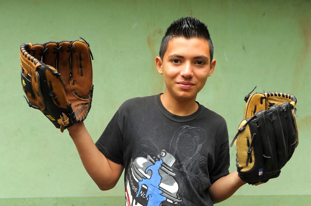 Carlitos holds two baseball gloves in his hands