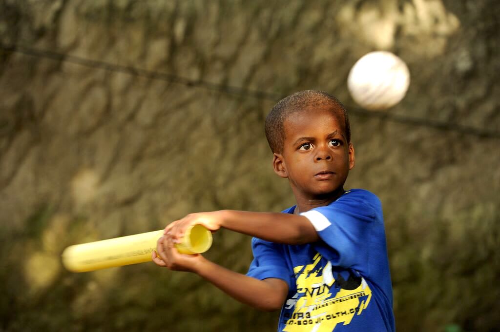 Little Oliver is wearing a blue shirt, trying to hit a white ball with a make-shift bat.