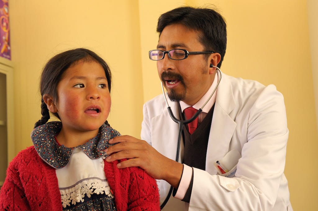 A doctor performs a check-up for a young girl using a stethoscope.