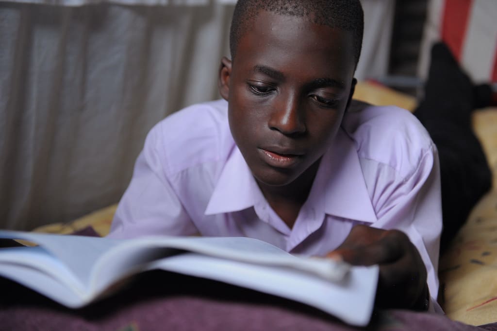 A teen boy reading a book.