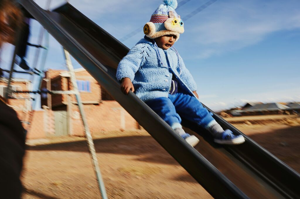 Little girl slides down the slide in knitted hat