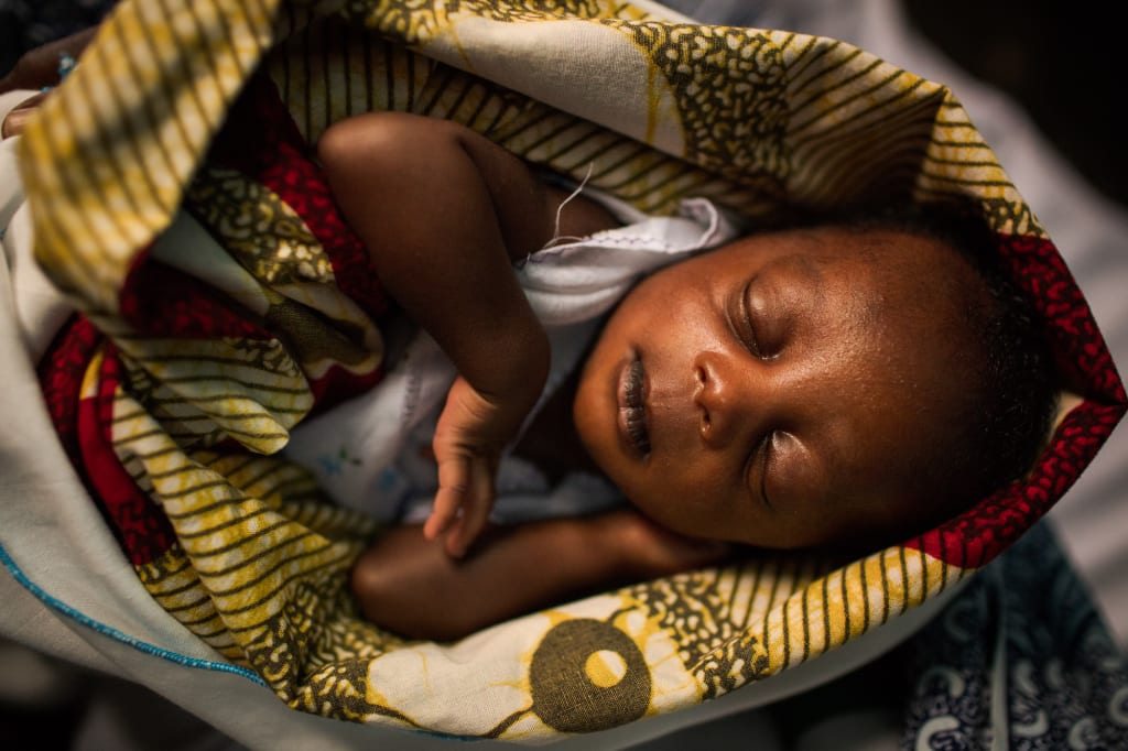 Baby from Africa in a blanket sleeping.