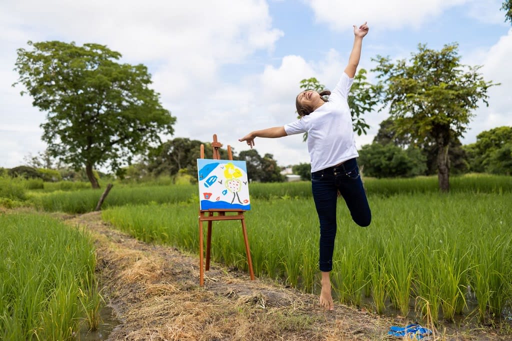 Girl skipping and dancing in front of her painting