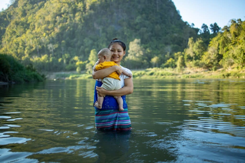 Mother holding her baby in the middle of the river