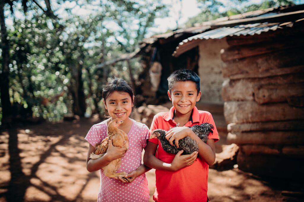 Neighbours Yessica, 8, and Argelio, 10 hold chickens