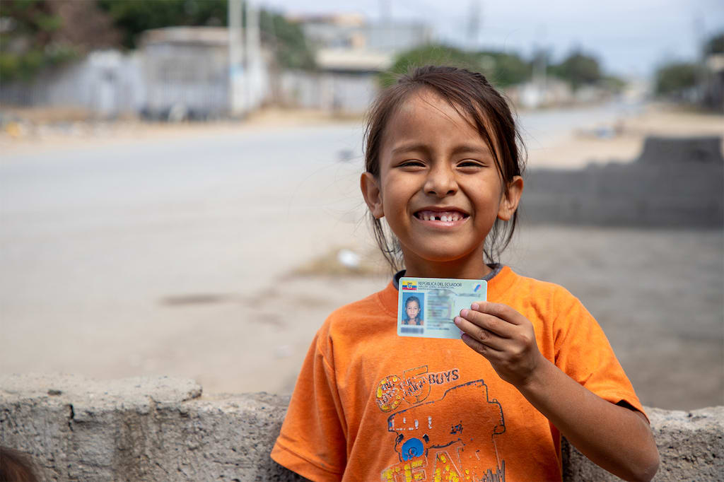 Maria Belen smiles and holds up her identity card.