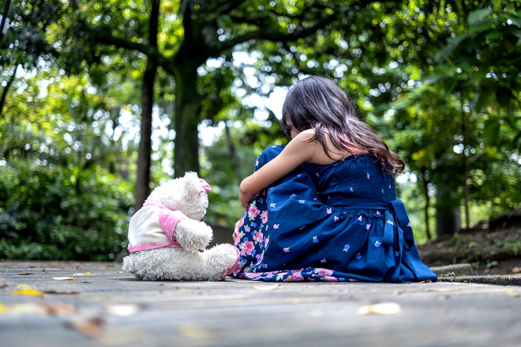 a small girl and a teddy bear face away from the camera