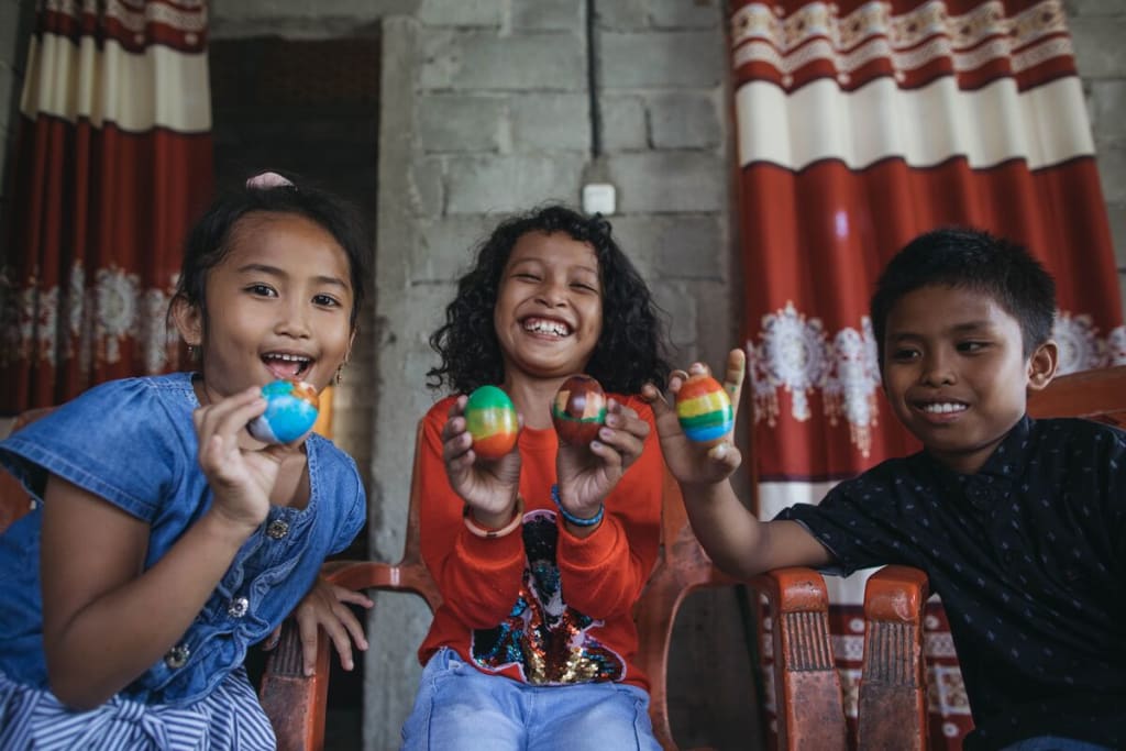 Three children hold up Easter eggs