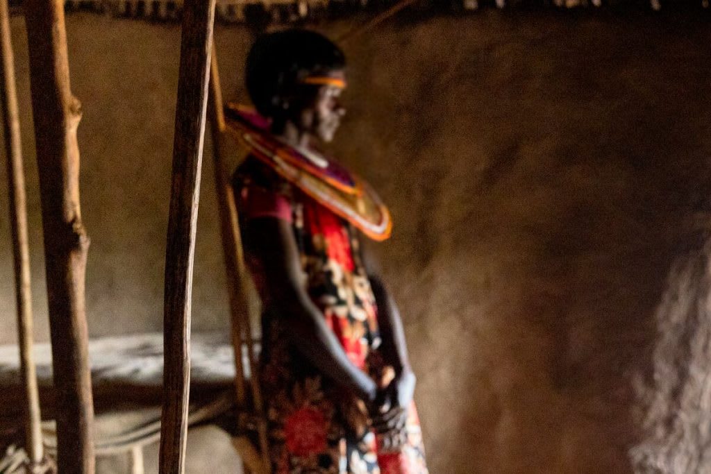 A Kenyan woman in a small home wearing traditional clothing