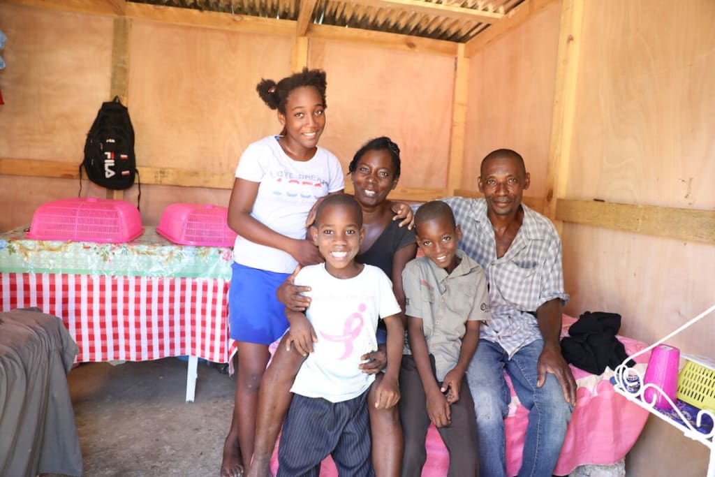 A family sits inside their home and smiles together