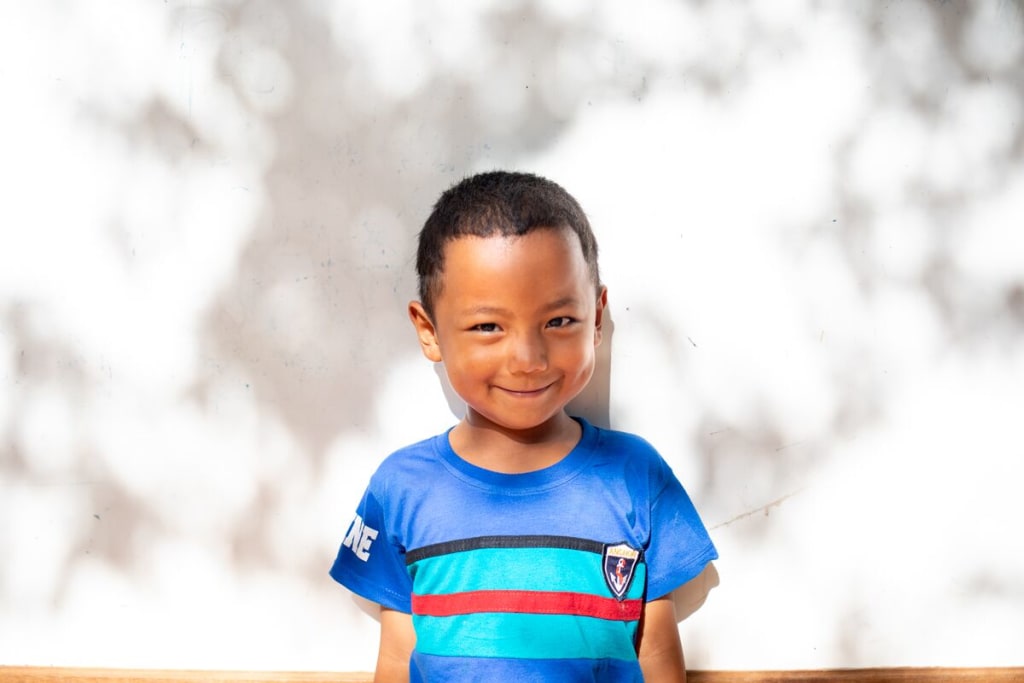 A boy in a blue striped shirt smiles at the camera