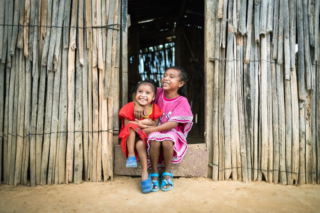 Two girls sit in a doorway and smile
