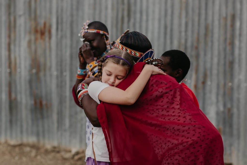 A woman wearing a red dress and traditional accessories, hugs a little girl