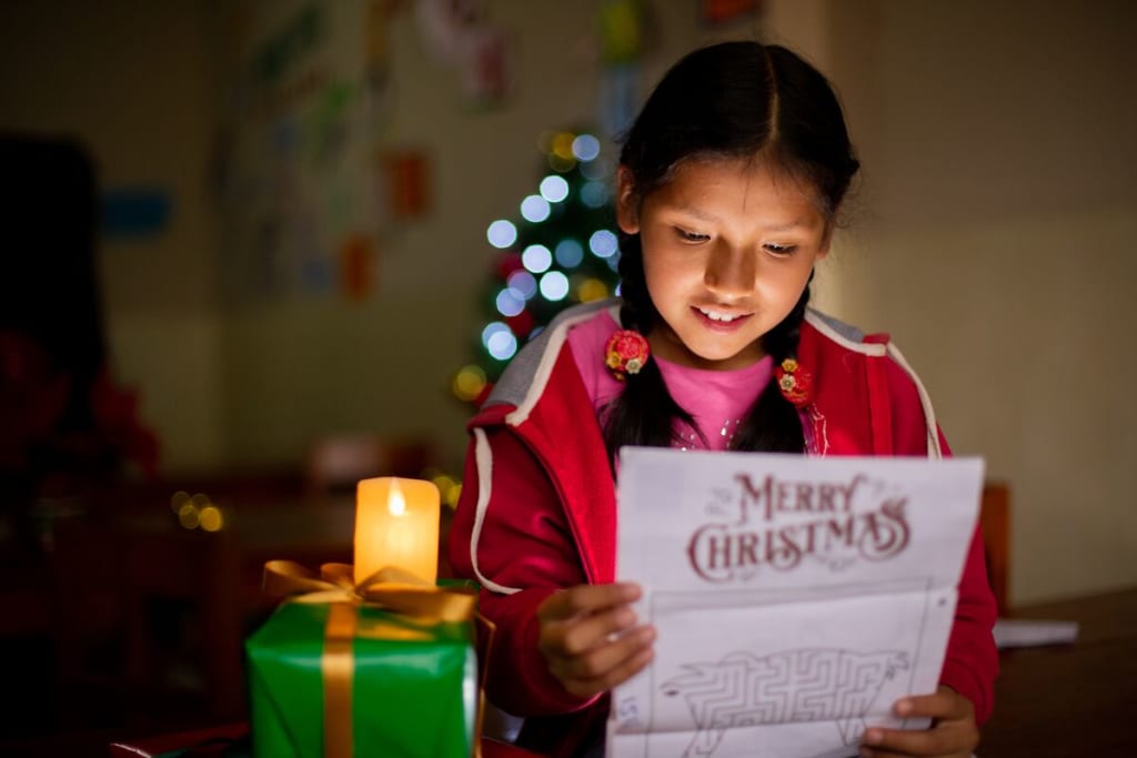 A girl in red reads a letter that says Merry Christmas