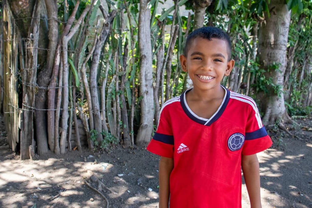A boy in a red shirt smiles at the camera