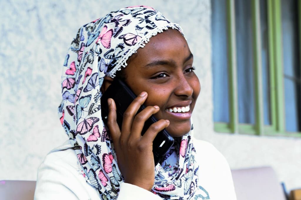 Fatie smiles as she talks on the phone.