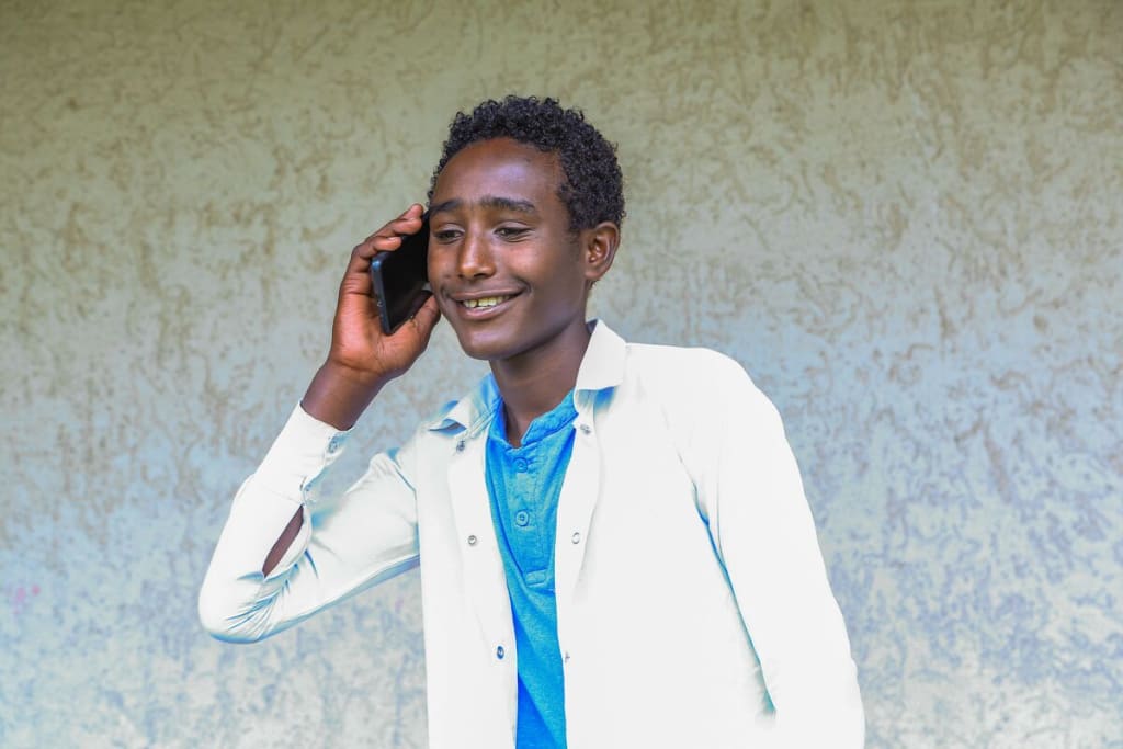 Young man talks on the phone while smiling.