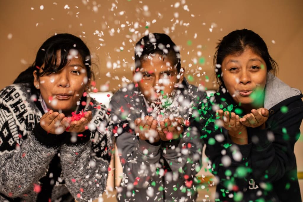Three teens blow red, white and green confetti at the camera
