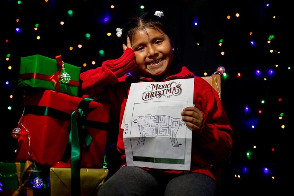 A girl in red holds up a Christmas letter and smiles