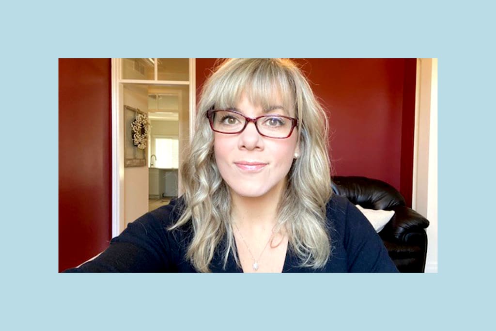 Misty in her home office, wearing glasses and a navy top.