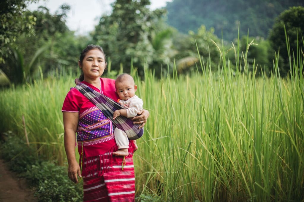 Muchunu and her granddaughter, baby Sathinee, outside their home in Thailand.