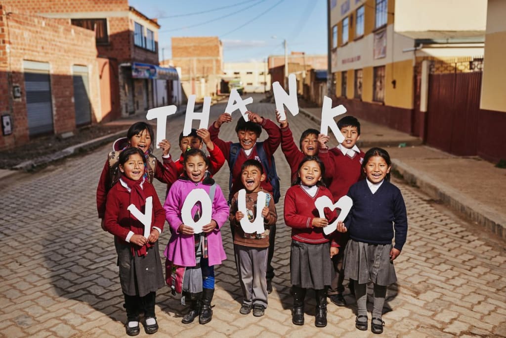 A group of kids hold up letters that say "thank you"