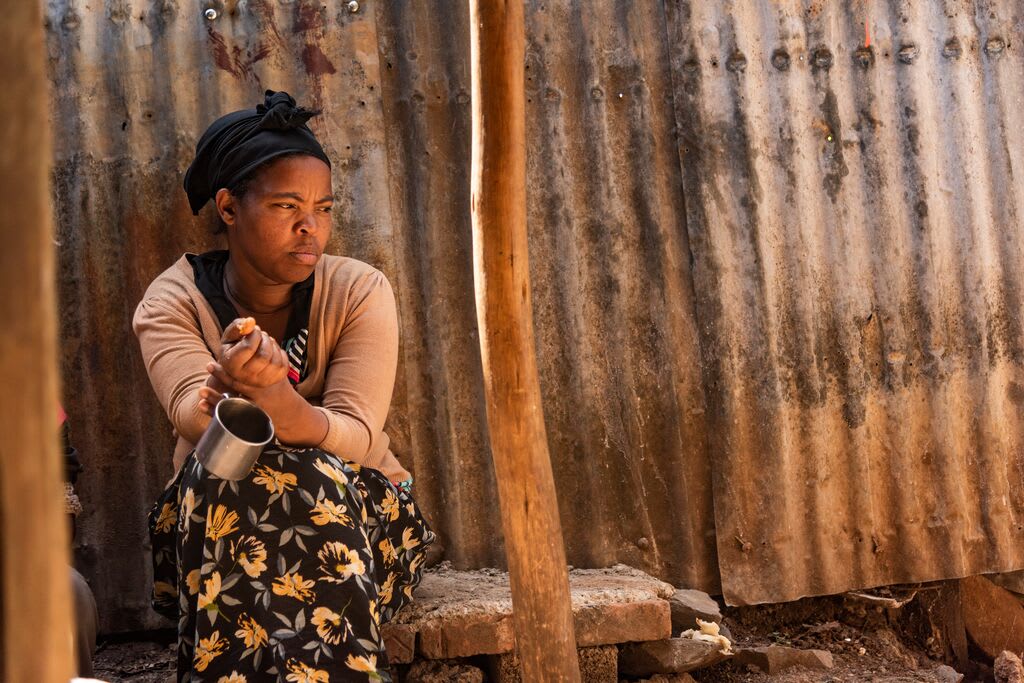 Abiyot is pictured outside her home holding a cup in her hand. She looks upset.