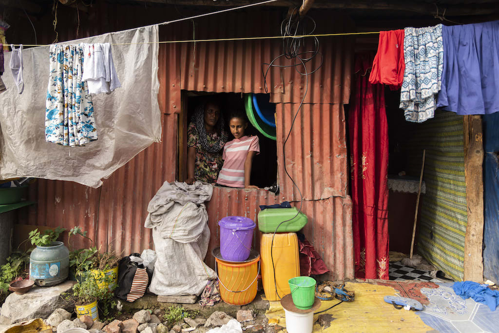 Meseret and Saron stand in the window of a small home.