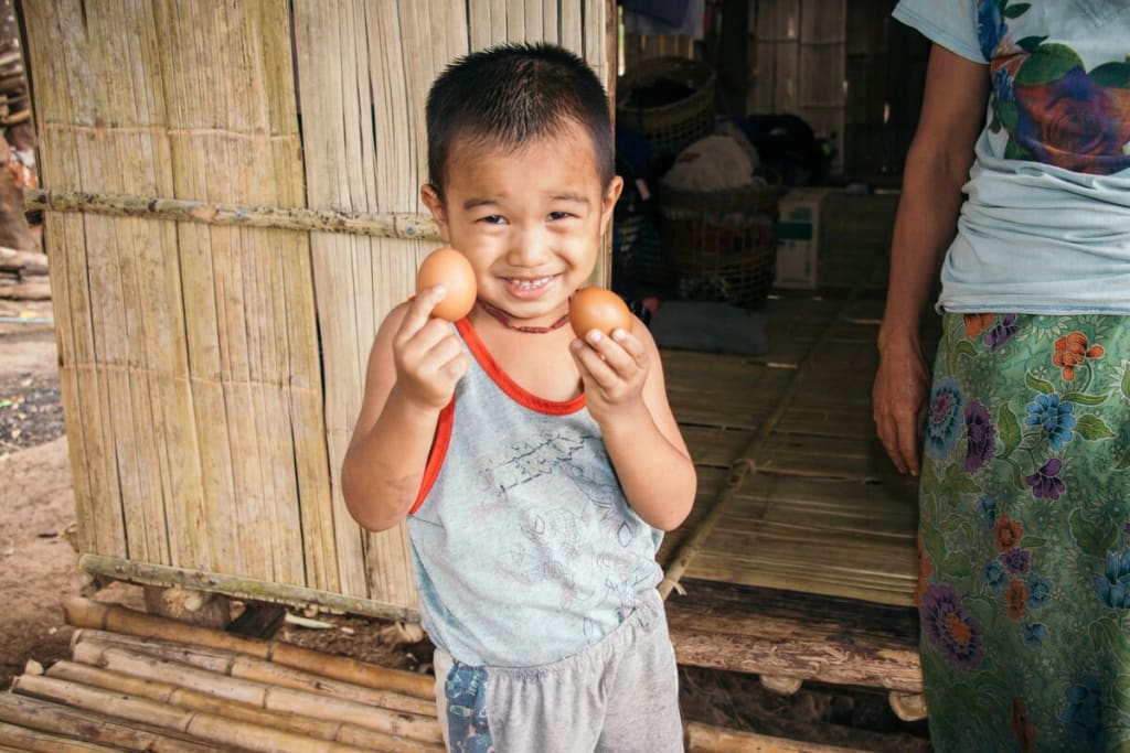 Little boy holds an egg in each hand and smiles big