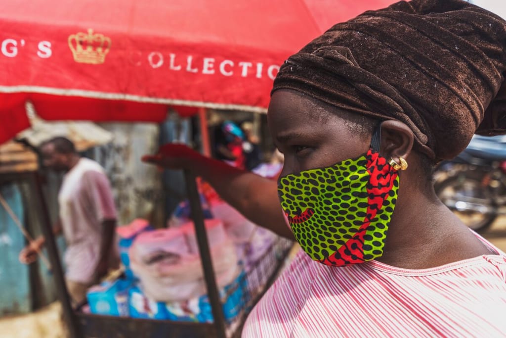 A close up picture of a woman with a green mask under a red outdoor tent