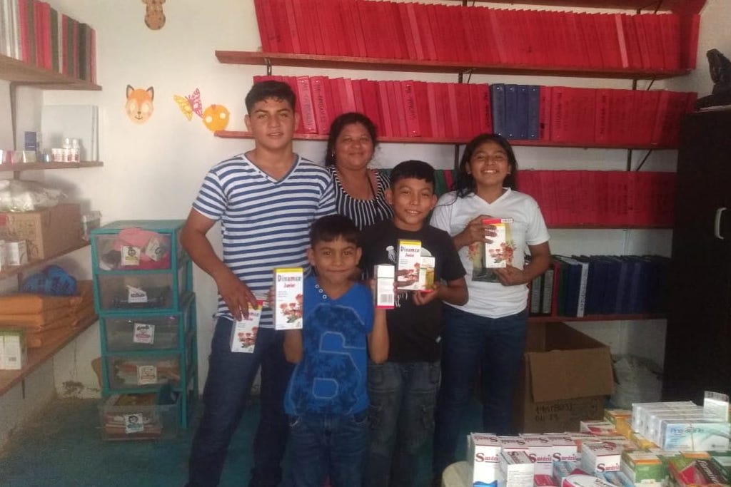 A family posing with vitamins, in the Compassion centre office.