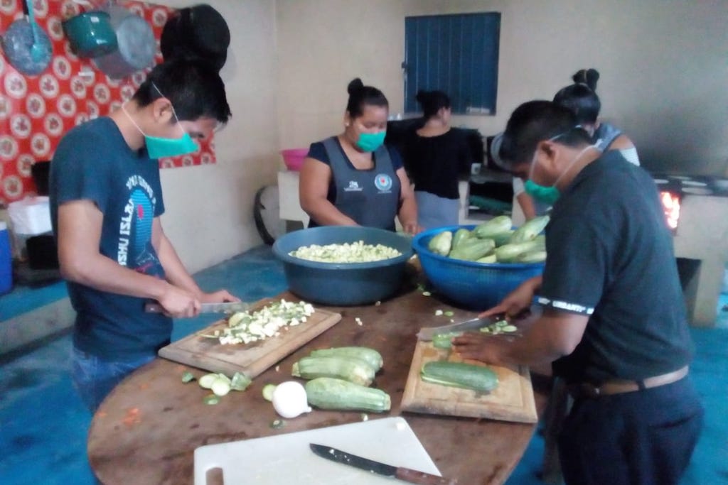 Compassion staff stand at a table chopping vegetables.