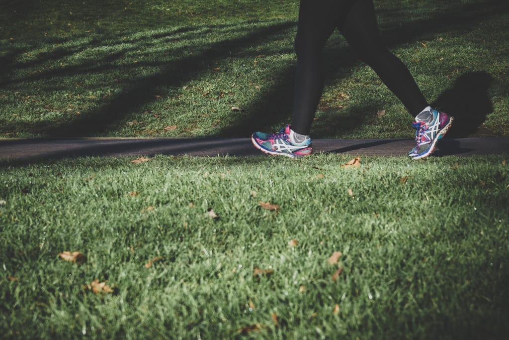 A pair of legs walking in a park.