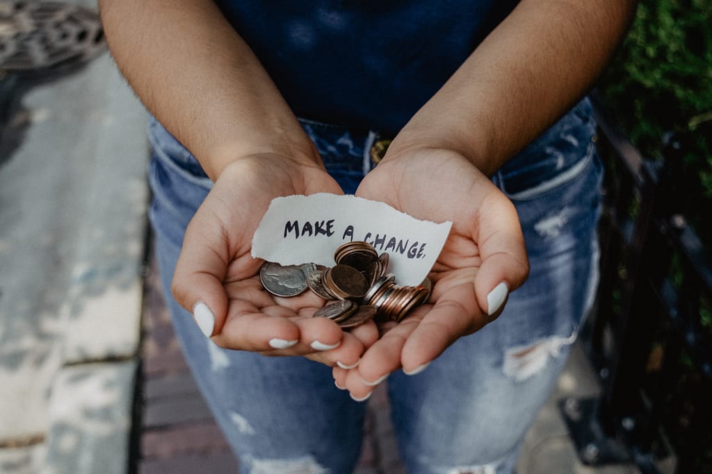 Girl holds change in her hands with a note that says, "Make a Change"