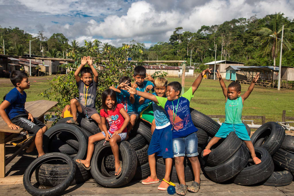 A group of Chachi children play on a pile of tires.