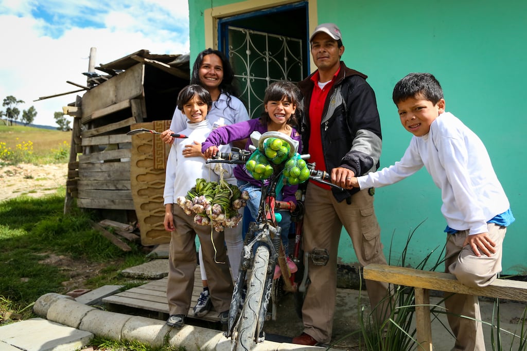 family of 5 smiles with fruit on their bicycle